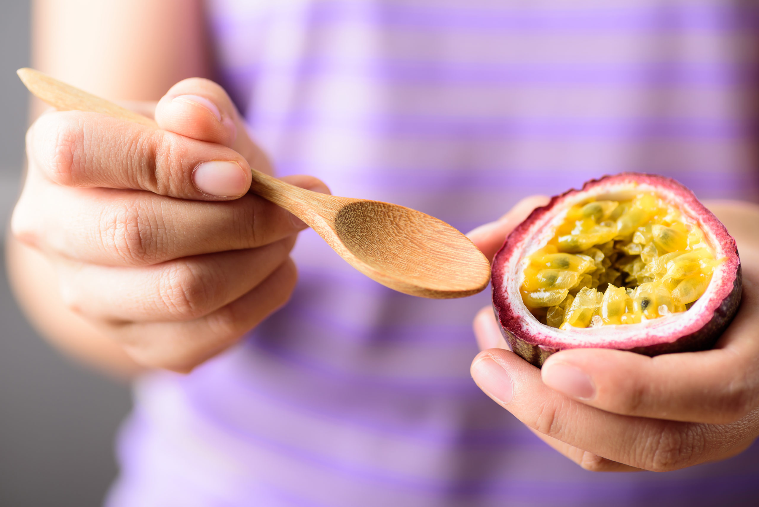 Hand holding spoon for eating passion fruit